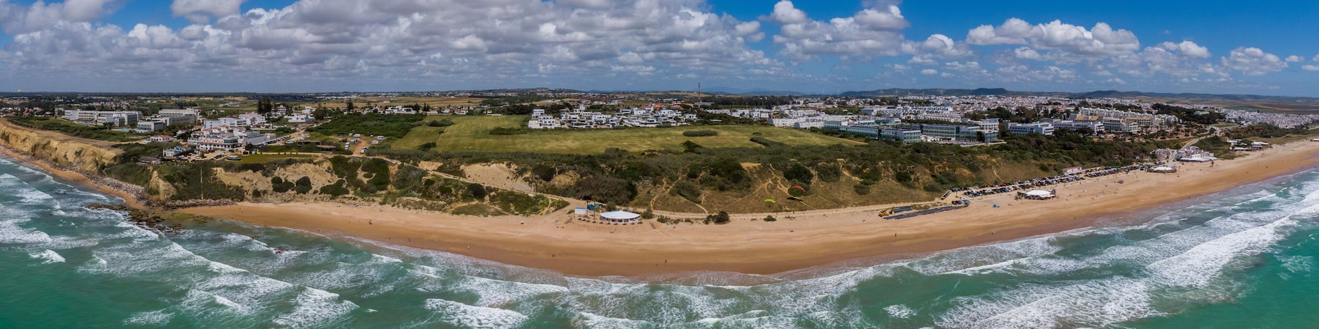 A coastal town with a beach, waves, and a clear sky.