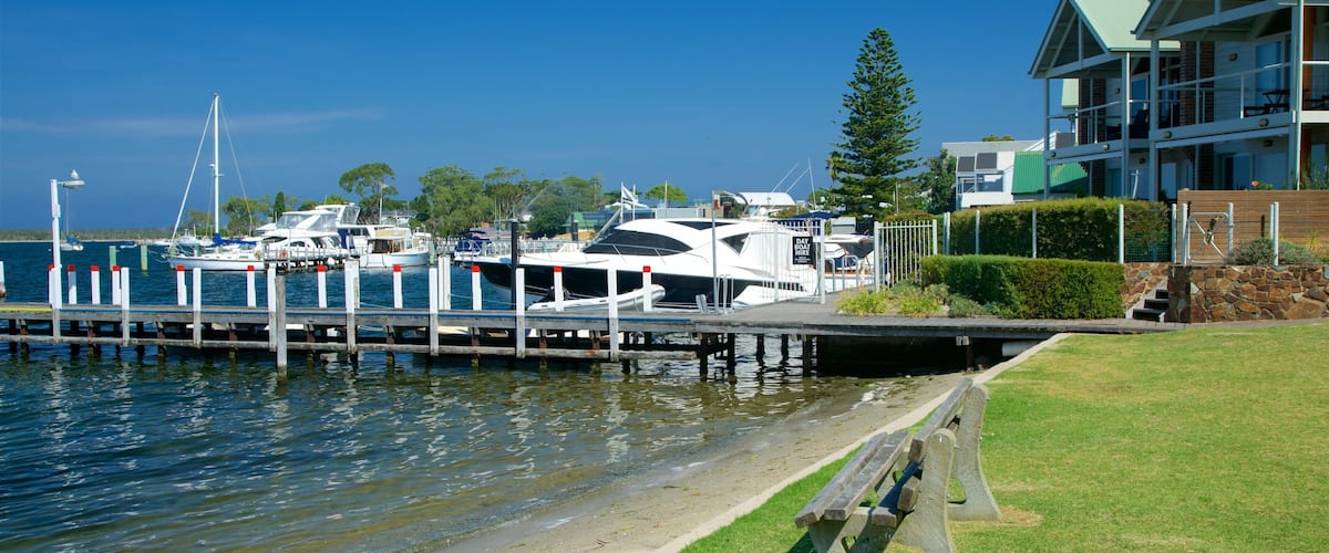 A marina with boats docked, a grassy area, and a building with a green roof.