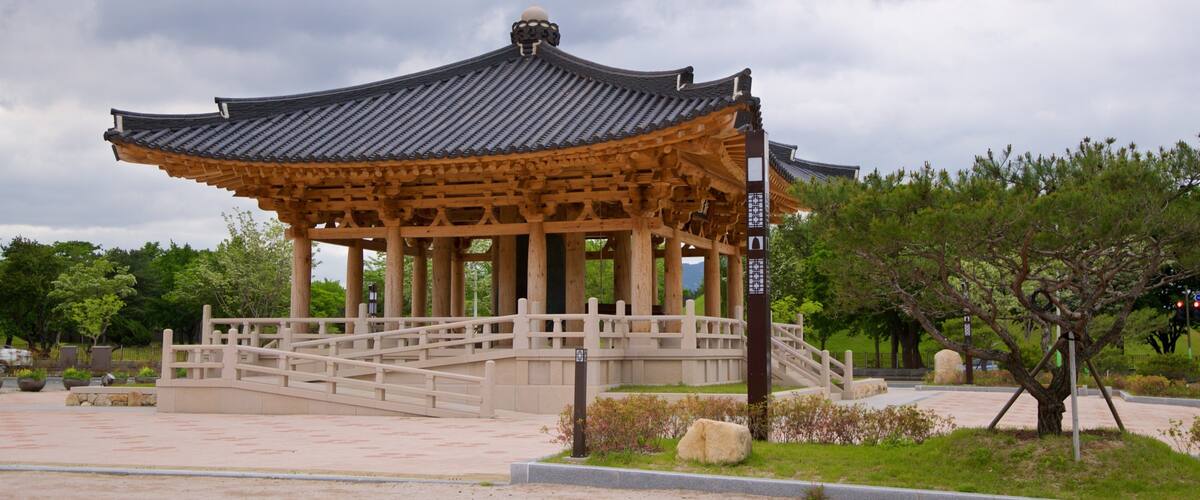 A traditional Korean pavilion with a tiled roof, wooden columns, and a stone pathway leading to it.