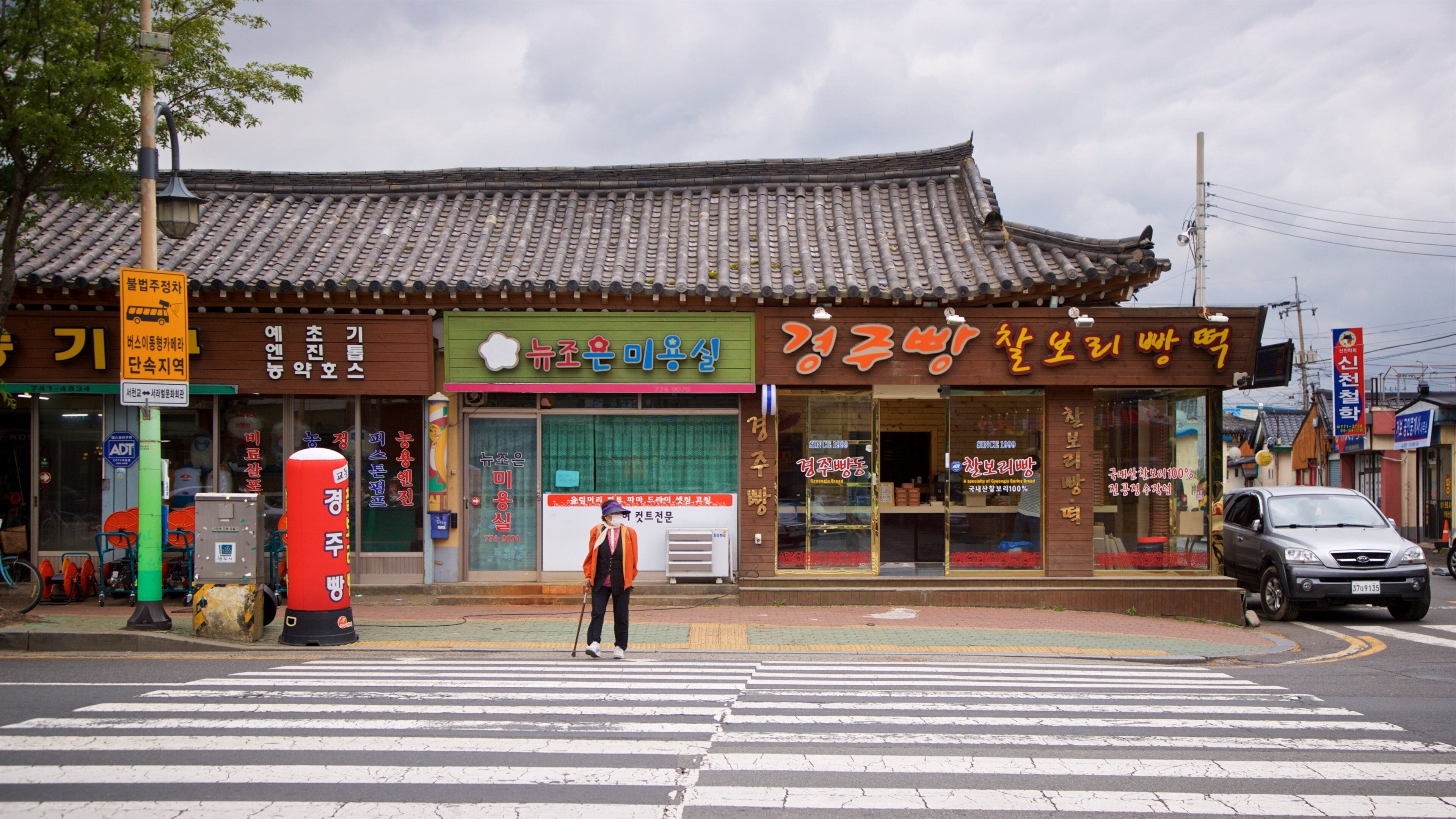 Fachada tradicional coreana com telhado de azulejos e letreiros em coreano.