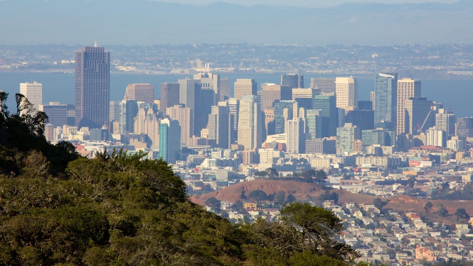 A cityscape with a prominent skyscraper, dense urban buildings, and a hilly landscape in the foreground.