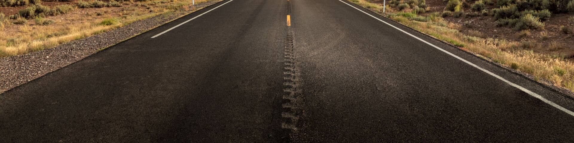 Long straight road in Utah with dramatic clouds and rain rolling in