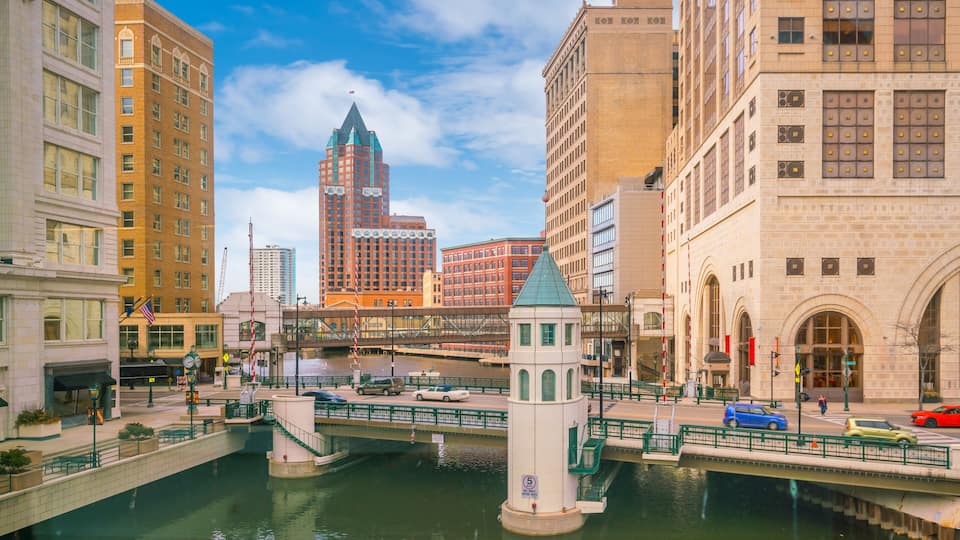 A cityscape with a river, a tower, and several buildings.