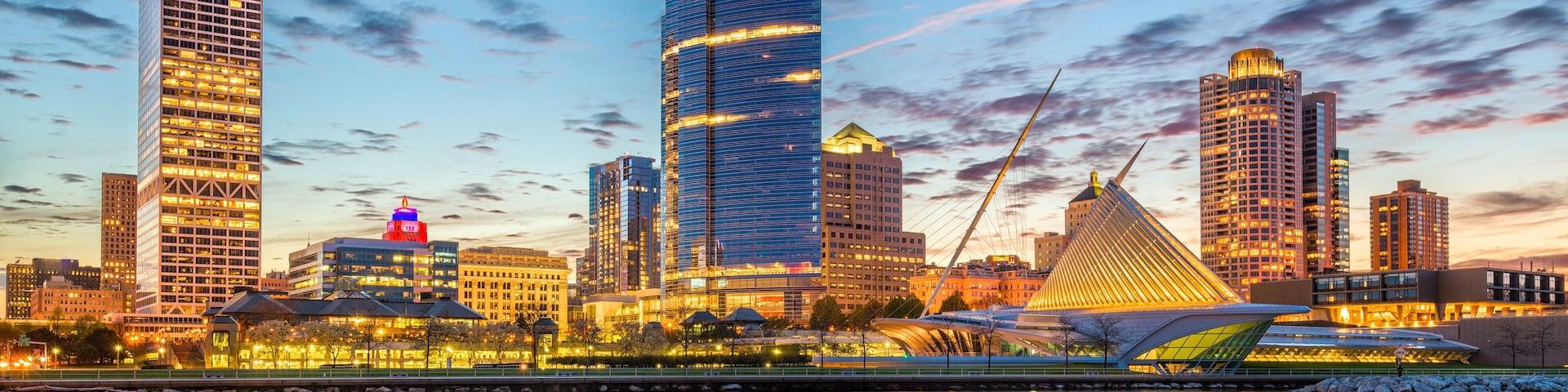 A city skyline with modern skyscrapers and a river in the foreground.