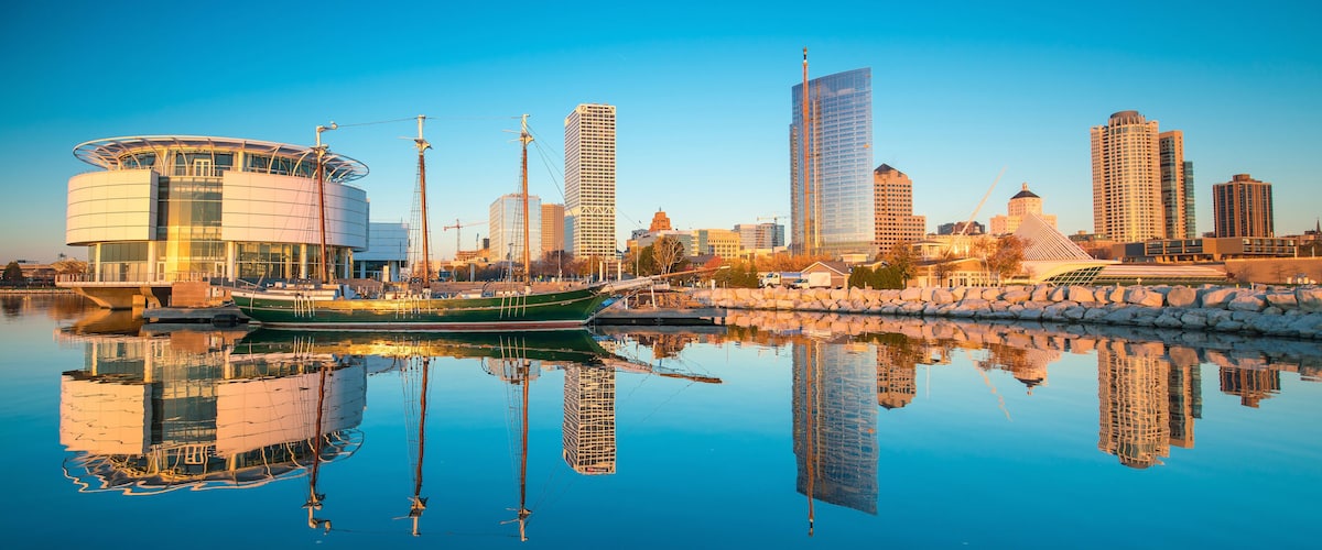 Milwaukee skyline at twilight with city reflection in lake Michigan and harbor pier.