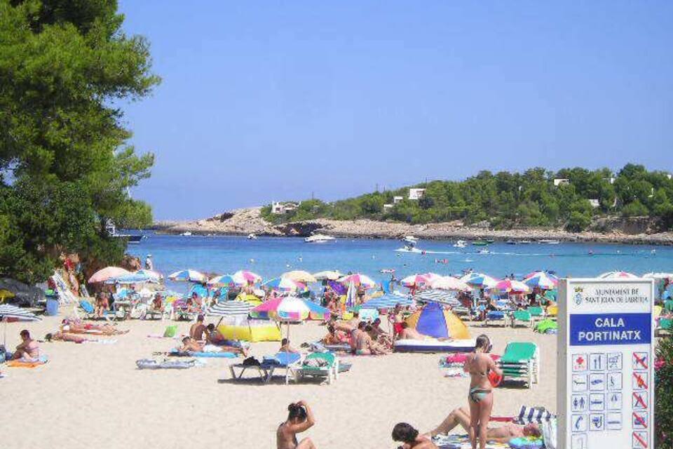 A crowded beach with colorful umbrellas and people sunbathing.