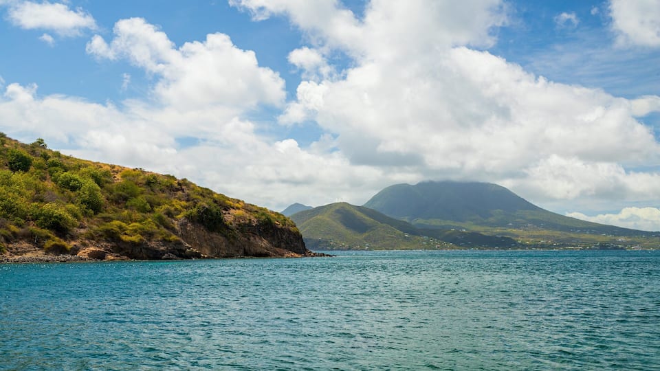 A coastal landscape with a mountain in the background and a clear sky.