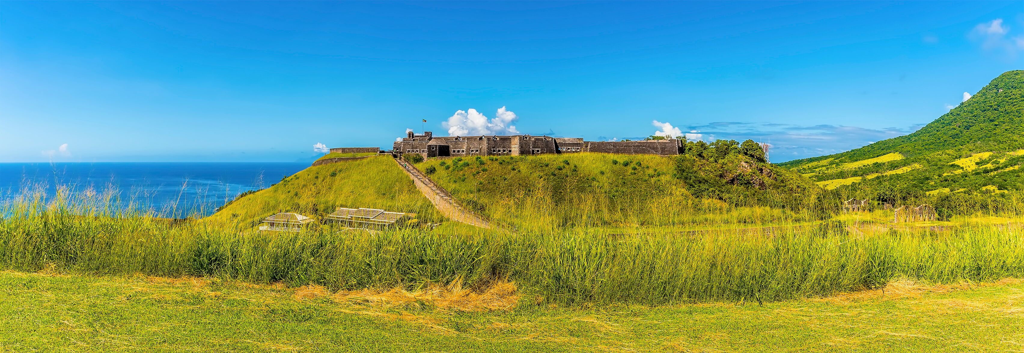 A historic fort on a grassy hill overlooking the ocean.