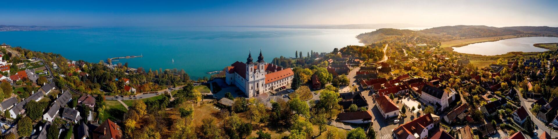A coastal town with a prominent church, a lake, and surrounding hills.