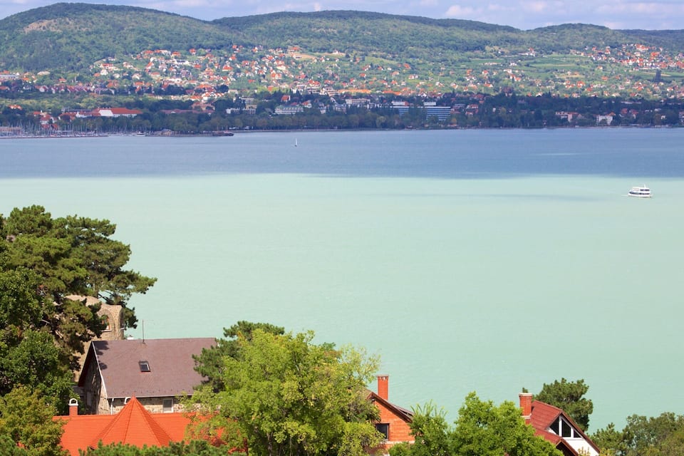 A lake with a town on the opposite shore, surrounded by hills.