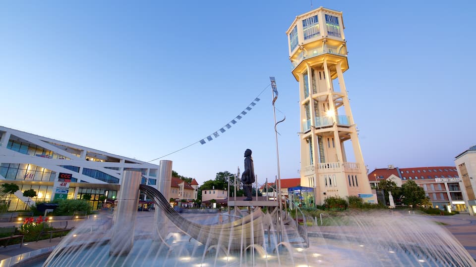 A tower, a statue, a fountain, and modern buildings.