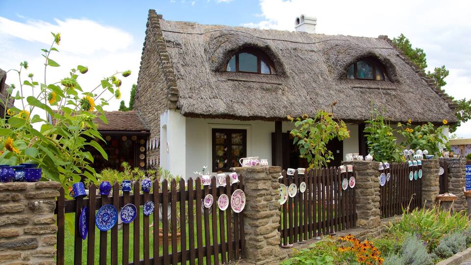 A thatched-roof house with a stone wall and a wooden fence adorned with ceramic plates.