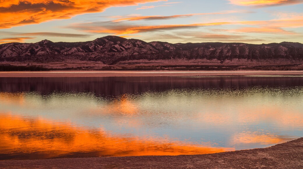 Sunset Spring Mountain Lake - Colorful stormy clouds rolling over a melting ice lake, with snow mountain range reflection, as spring sun sets.