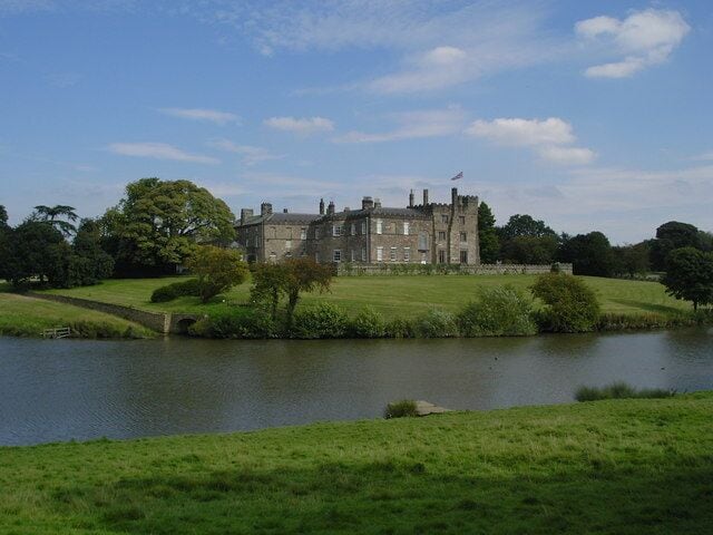 A large castle by a lake with a bridge leading to it.