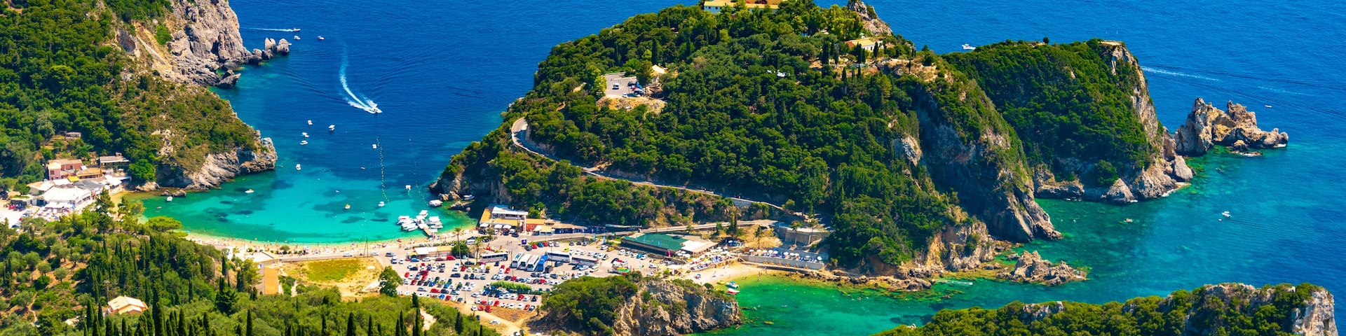 A coastal town with a marina, lush green hills, and clear blue waters.