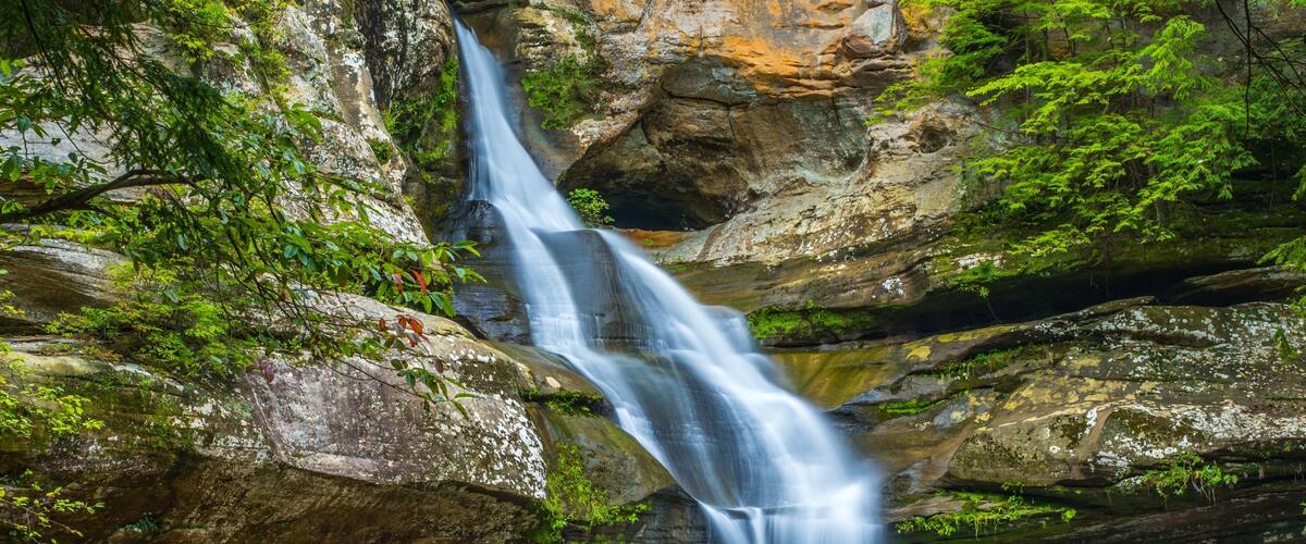 A waterfall cascading over rocky terrain surrounded by lush greenery.