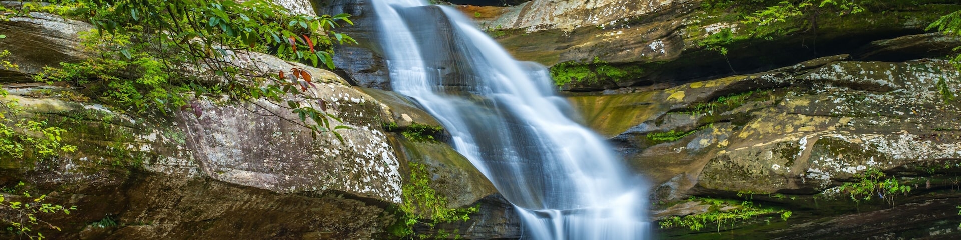 A waterfall cascading over rocky terrain surrounded by lush greenery.