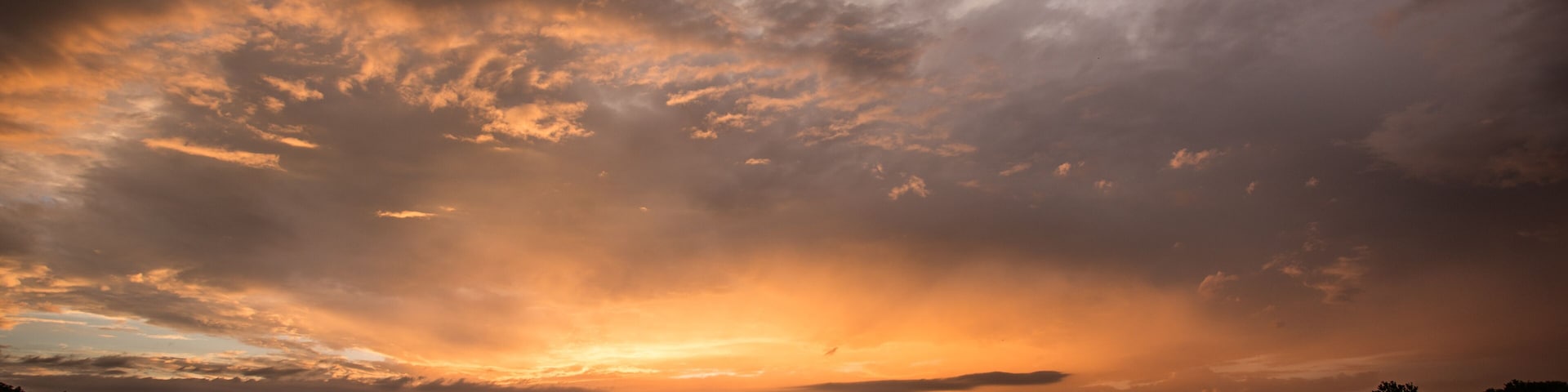 Pôr do sol sobre um rio, com céu nublado.