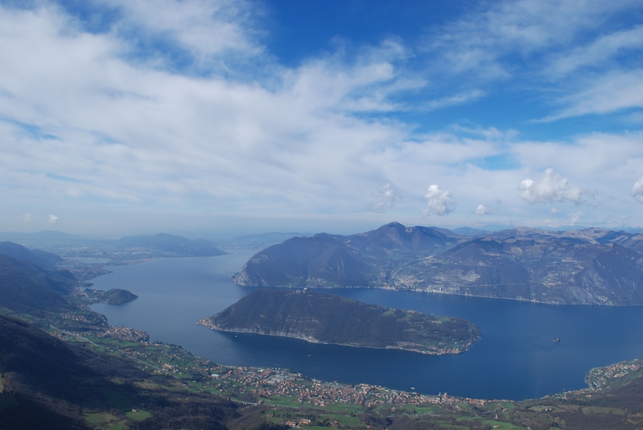 Paisaje montañoso con un lago grande y un pueblo en primer plano.