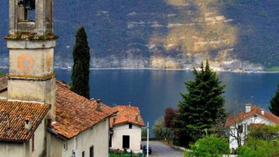 A coastal town with a church, a lake, and mountains in the background.