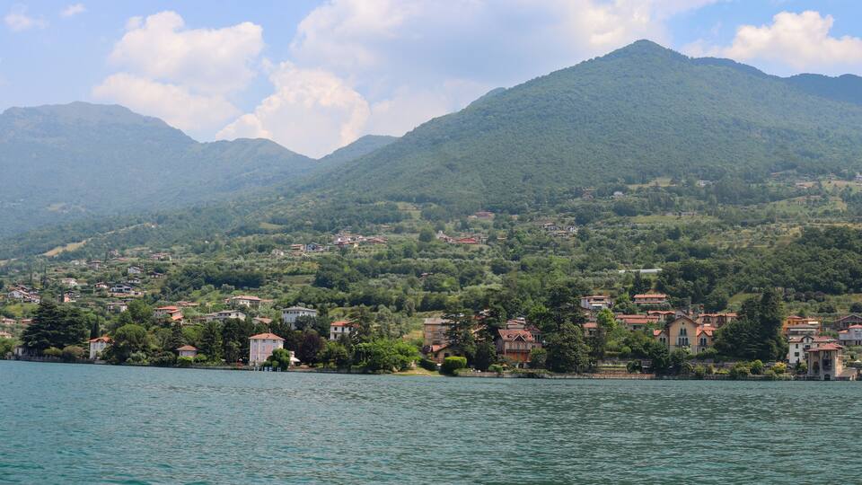 A lake with a town on the shore, surrounded by mountains.