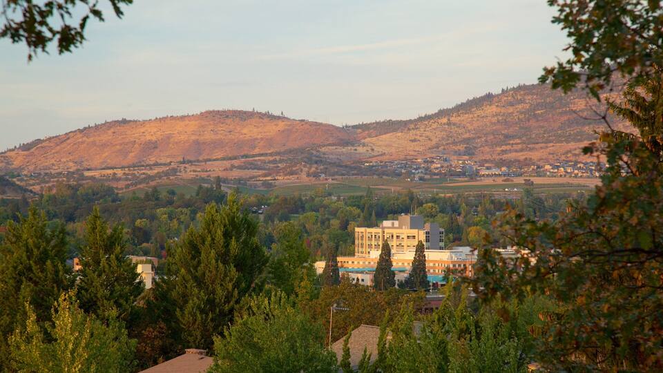 Un pueblo situado en un valle, con un edificio destacado en primer plano y colinas al fondo.