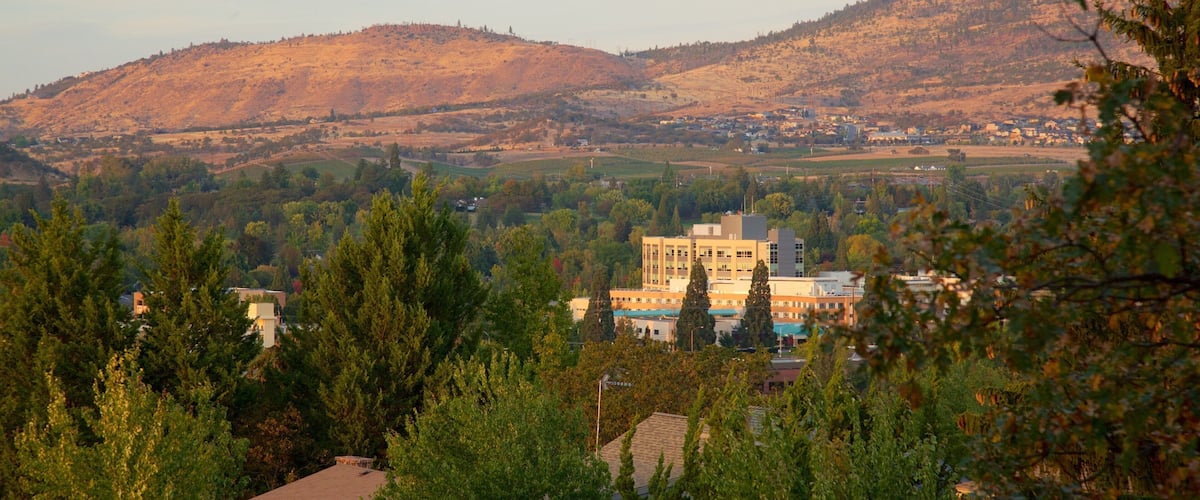 A town nestled in a valley with a prominent building in the foreground and hills in the background.