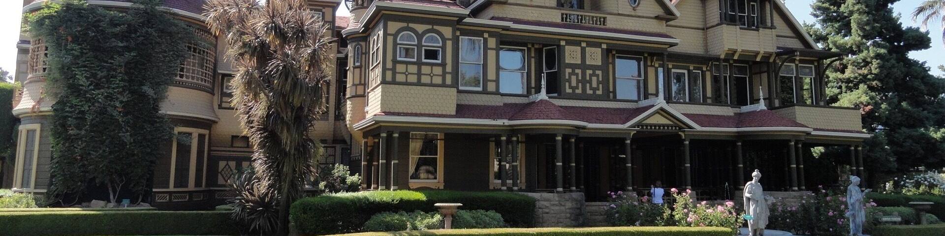 A large, ornate Victorian-style mansion with multiple towers and a well-manicured garden.