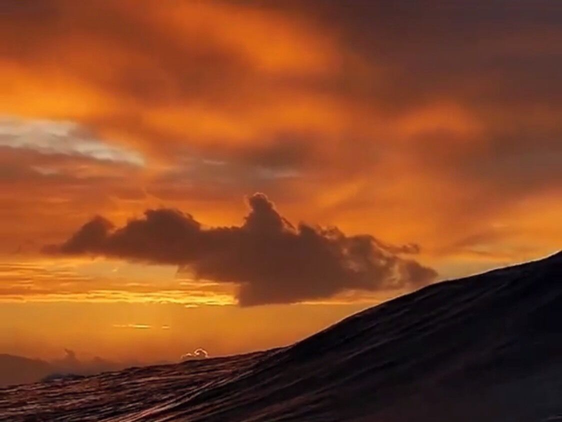 Un atardecer sobre un paisaje montañoso con una formación nubosa destacada.