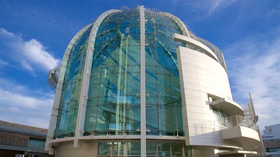 A modern building with a large glass dome and white exterior walls.