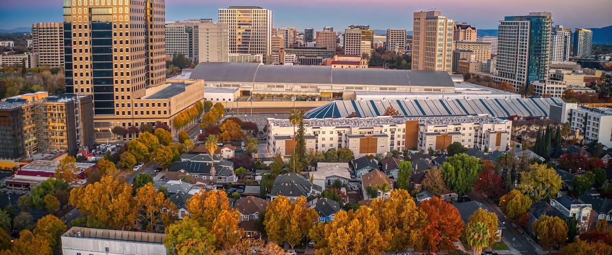 A cityscape with autumn-colored trees, a large stadium, and various high-rise buildings.