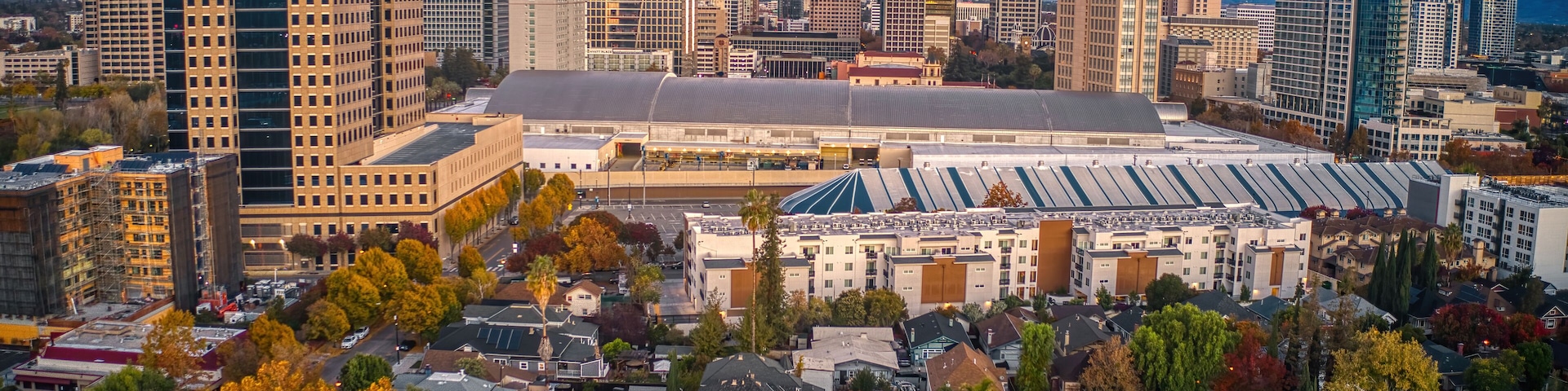 A cityscape with autumn-colored trees, a large stadium, and various high-rise buildings.