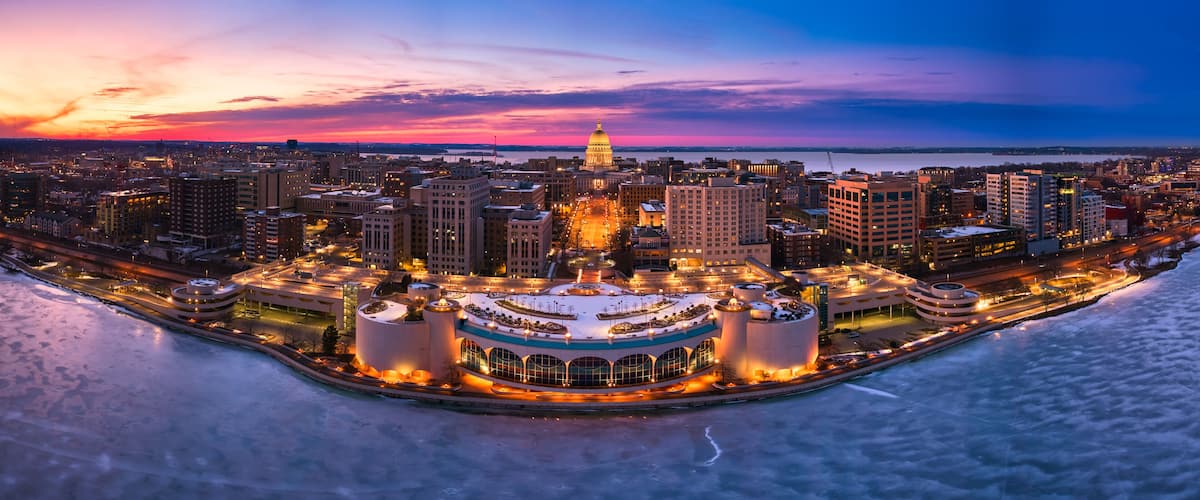 A cityscape at dusk with a prominent dome-shaped building, a waterfront, and a circular structure with multiple towers.