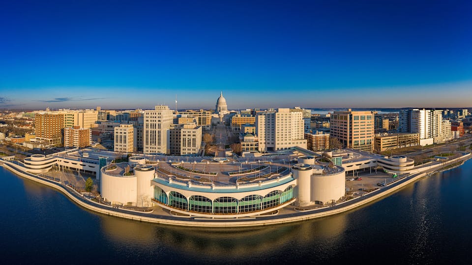 A cityscape with a prominent dome-shaped building in the center, surrounded by modern high-rise buildings and a waterfront promenade.