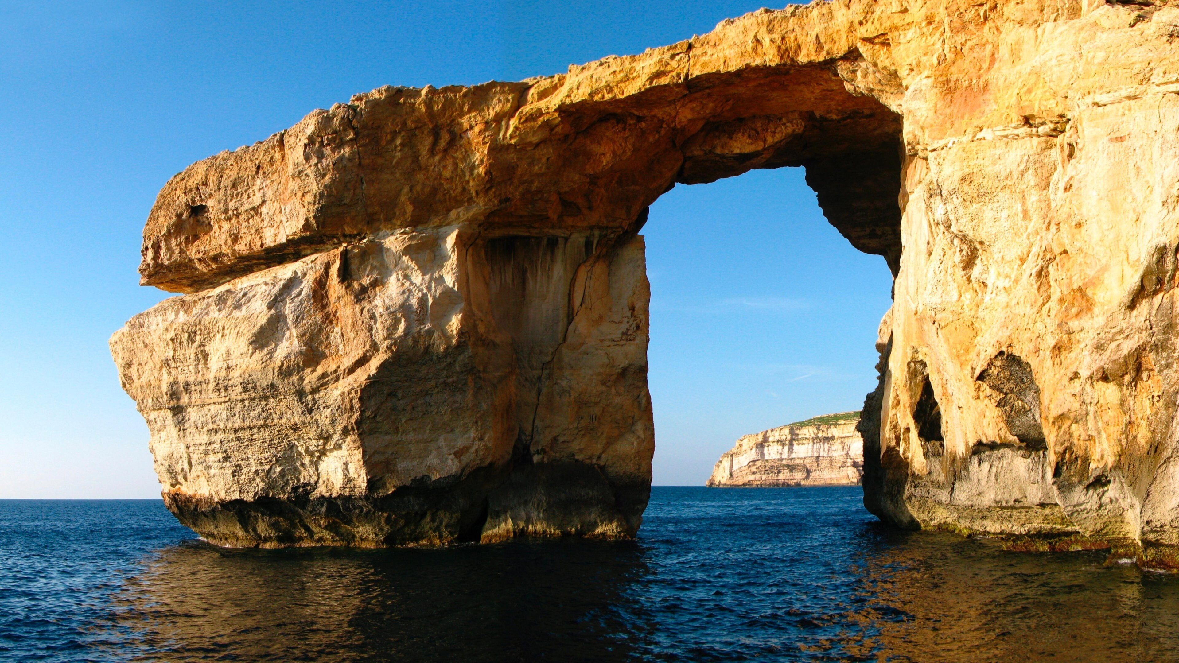 A natural rock arch formation over the sea.