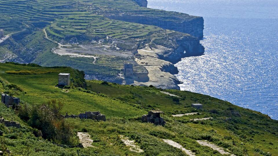 Terraced fields, a coastal cliff, and a small stone structure.