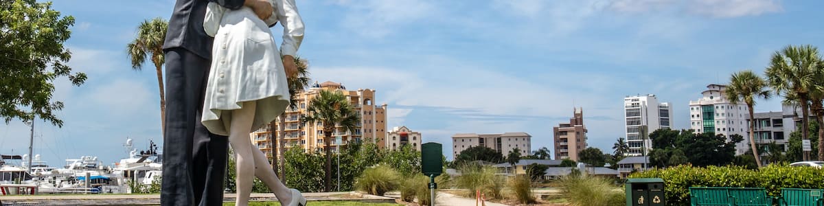 Une statue représentant un homme et une femme enlacés, sur une pelouse, avec une vue sur la ville en arrière-plan.