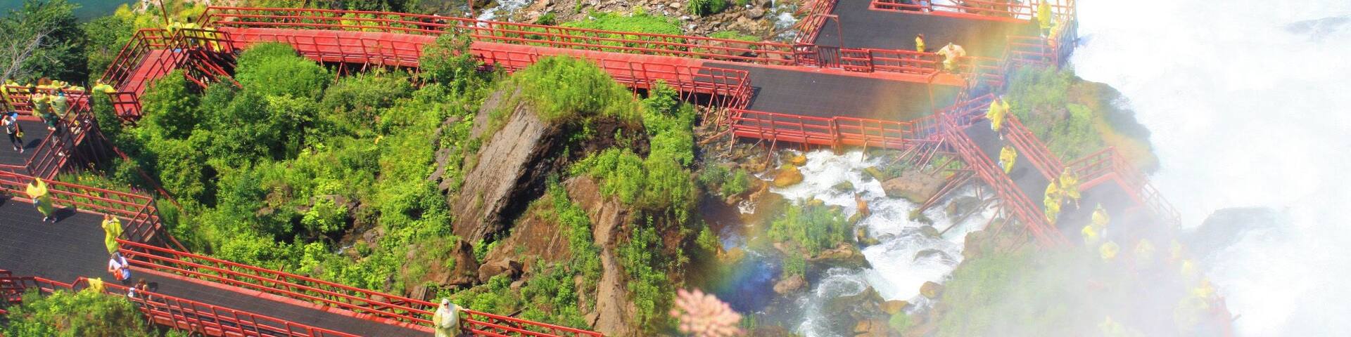 Une zone côtière avec un pont rouge enjambant une rivière, entourée de verdure et d’un paysage rocheux.