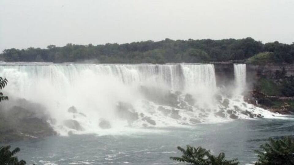 Une grande cascade dont l’eau dévale une falaise rocheuse.