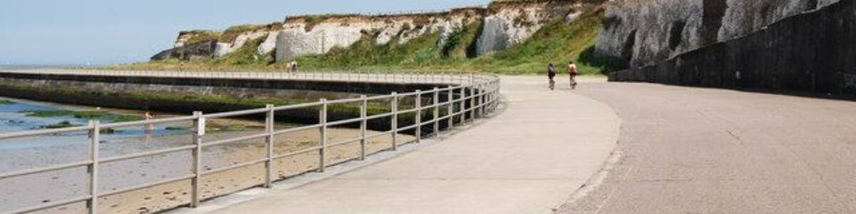 Ein Küstenweg mit Klippen und einer Seemauer.