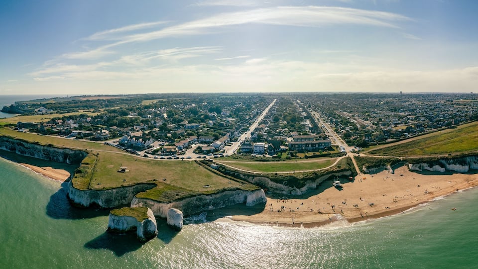 A coastal town with cliffs, a beach, and a road leading to the town center.