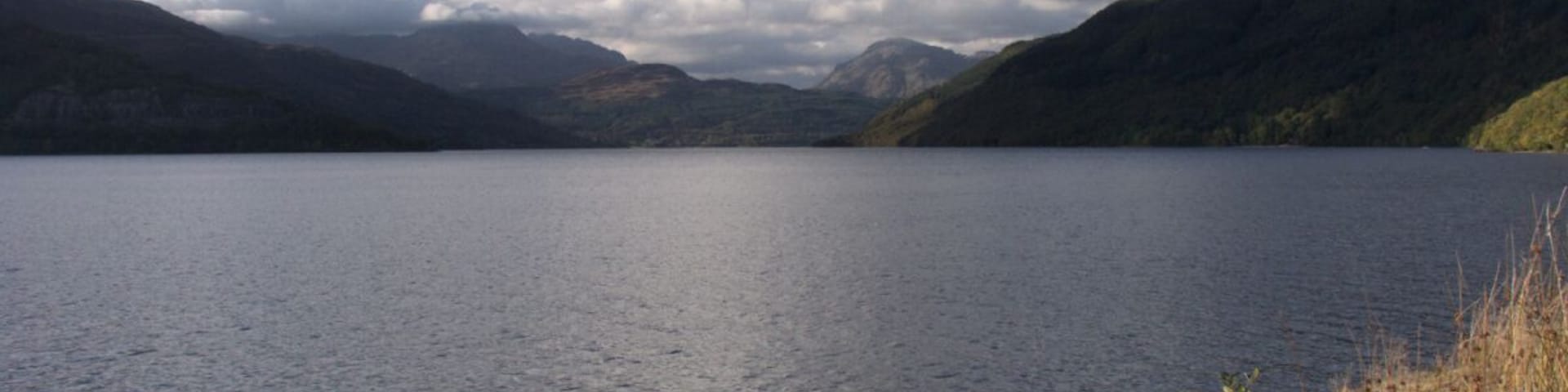 Un lago tranquilo rodeado de montañas y colinas cubiertas de hierba.