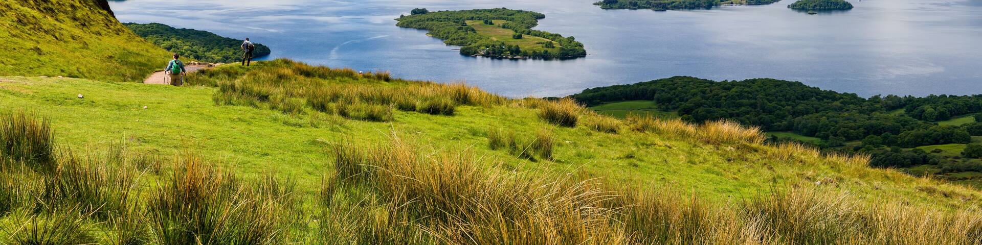 Hikers descending Conic Hill towards Loch Lomond with beautiful mountain scenery