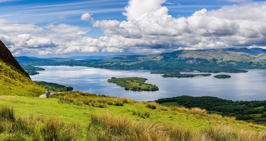 Hikers descending Conic Hill towards Loch Lomond with beautiful mountain scenery