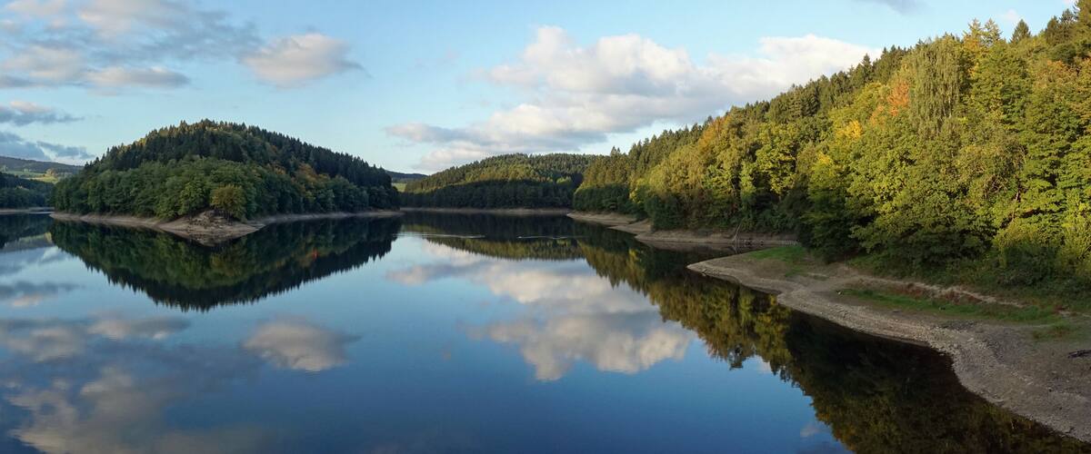 A calm lake surrounded by dense forests and hills.