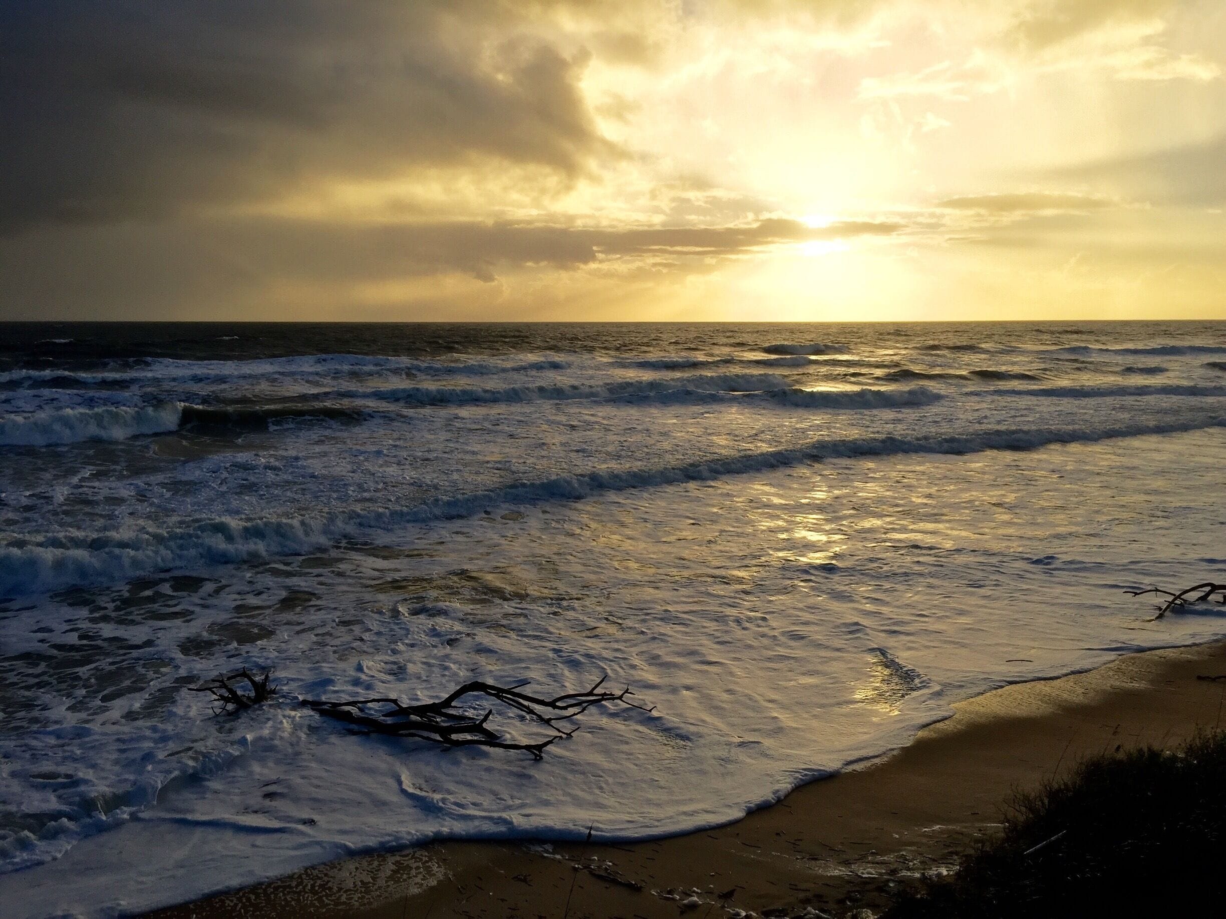 Une plage avec des vagues et un coucher de soleil.