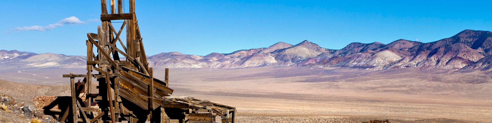 Old wooden mining hopper bin under blue sky in the Nevada Desert near a ghost town.