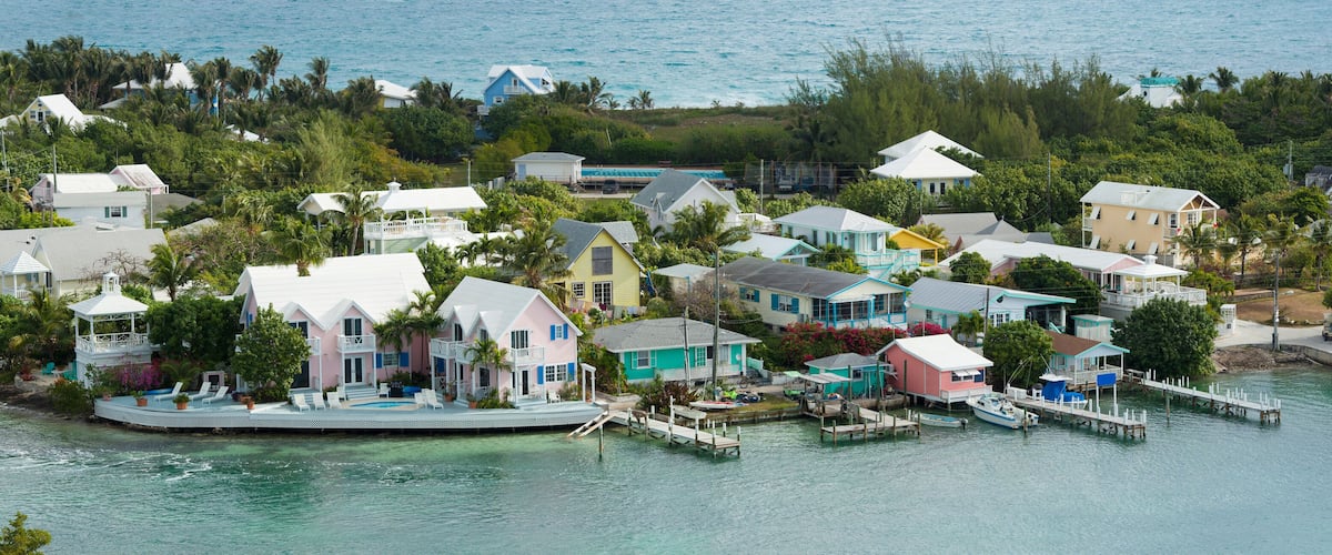 A coastal village with colorful houses, a dock, and clear turquoise waters.
