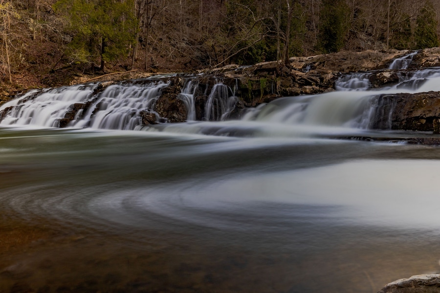 Una cascada que se precipita sobre rocas en un área boscosa.