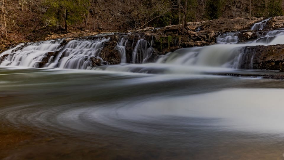 A waterfall cascading over rocks in a forested area.